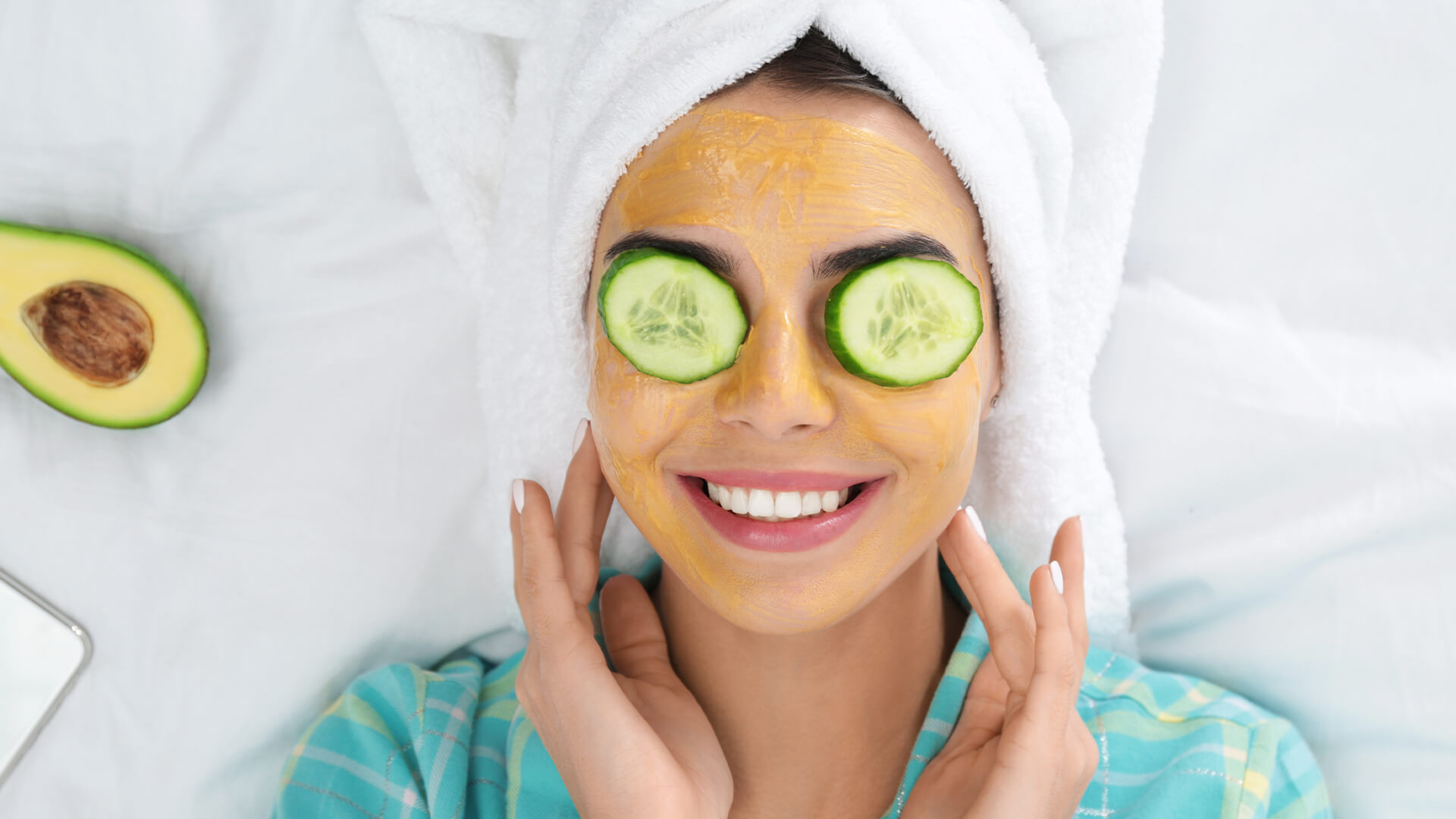 戴着口罩，眼睛上抹着黄瓜，头发用毛巾包着