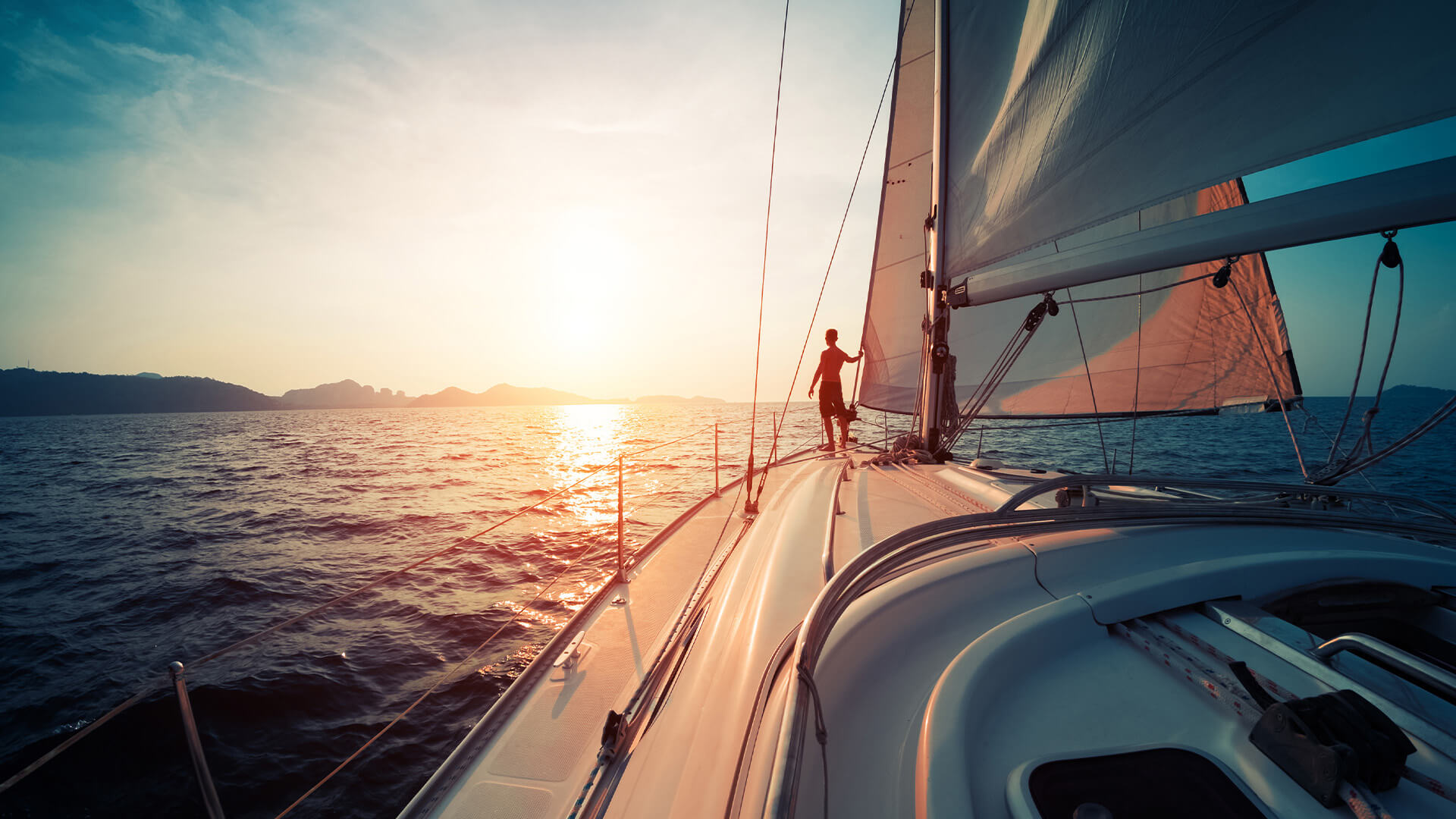 日落时，一名男子在一艘游艇的前部凝视着