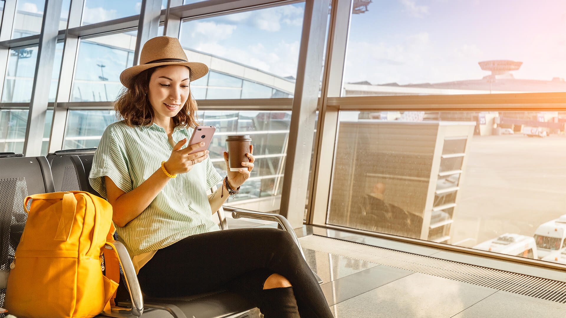 坐在机场休息室里拿着电话和咖啡的女人